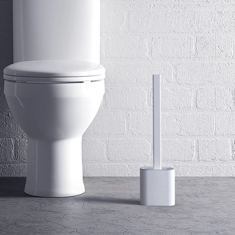 silikone toiletbørste der står på gulvet ved siden af toilettet